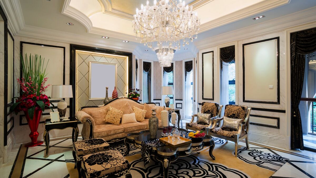 A formal salon with a crystal chandelier, panelled walls, silk-upholstered seating and a patterned marble floor