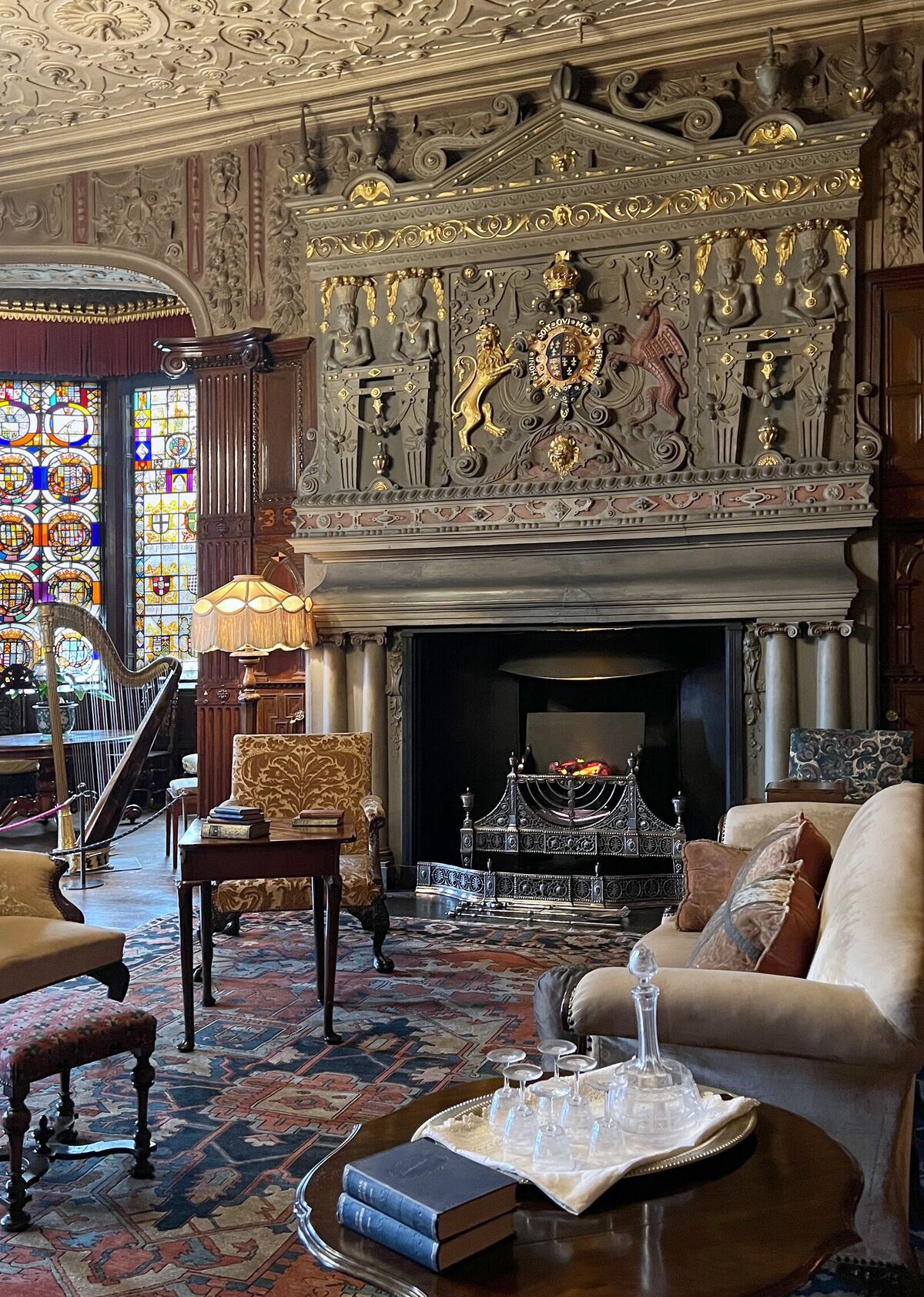 A Victorian drawing room with a carved overmantel, stained-glass window and cut-glass decanters set out on a polished table